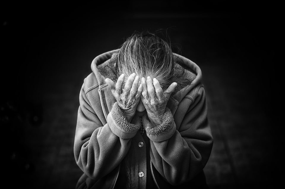 elder woman with hands over face